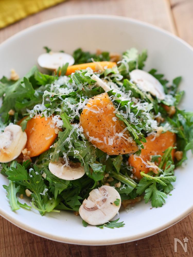 白色の丸皿に盛られた春菊と柿のサラダ