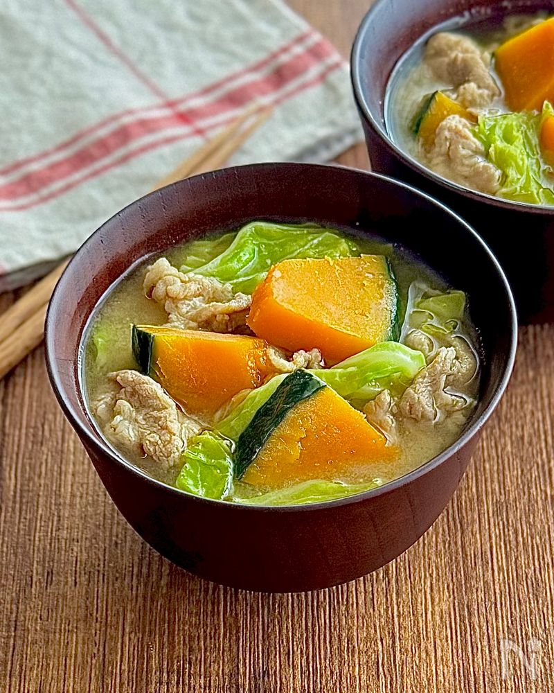 茶色の椀に盛られた豚肉とかぼちゃとキャベツの味噌汁