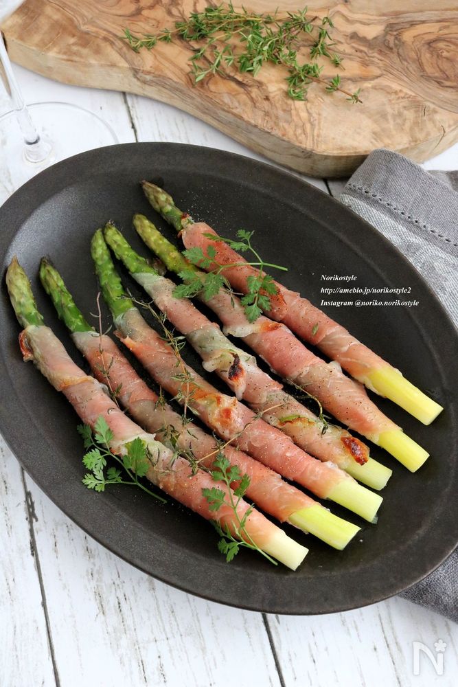 黒い皿にのった、生ハムとアスパラガスのロール焼き
