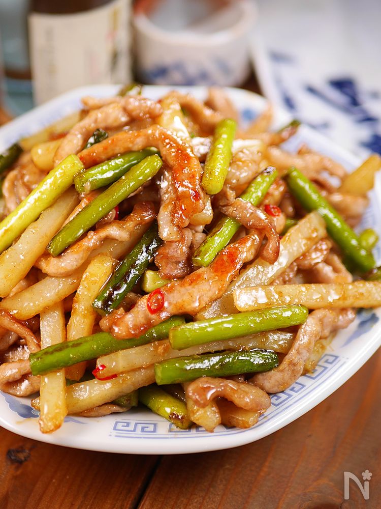 柄物の皿に盛りつけられたにんにくの芽とじゃがいもの和風青椒肉絲