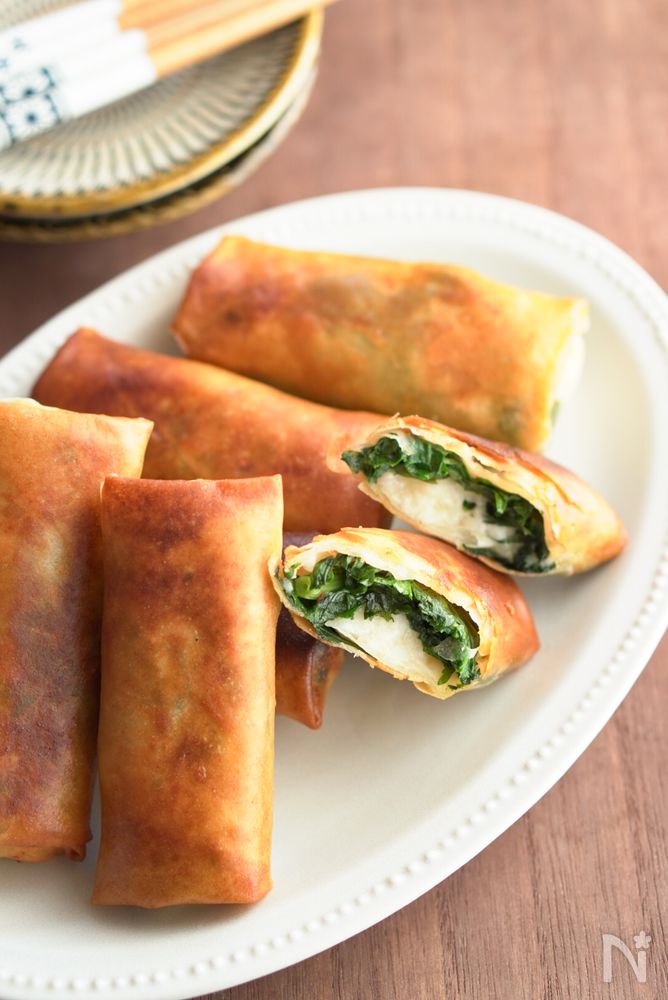 白い楕円型の皿に盛り付けた春菊とはんぺんの春巻き