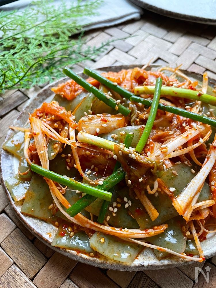 黒い皿に盛り付けたねぎと刺身こんにゃくのキムチサラダ