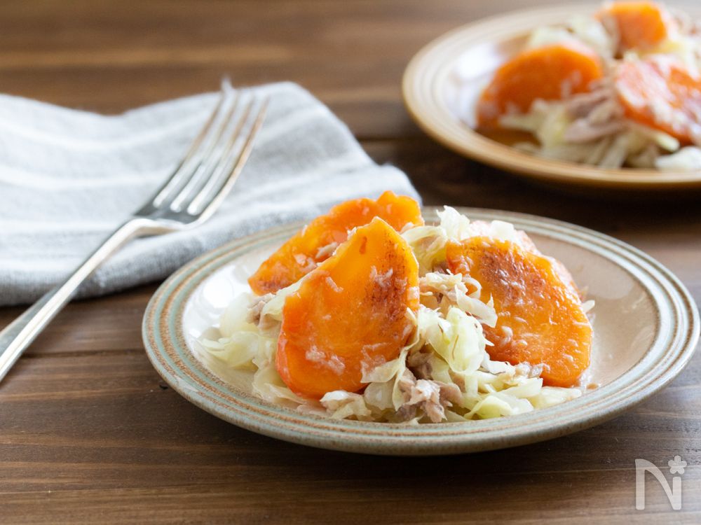 ベージュの丸皿に盛られた柿とキャベツとツナのサラダ