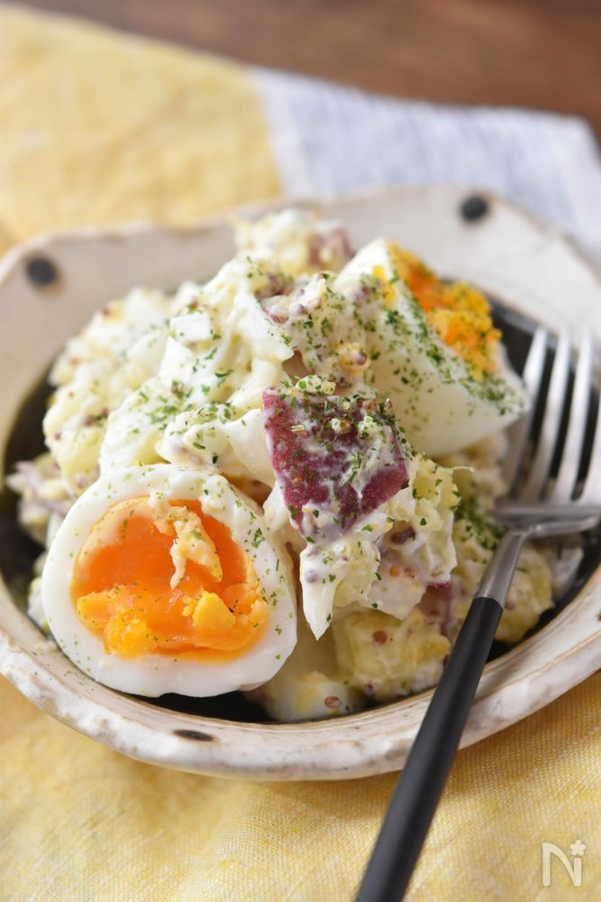 白色の皿に盛られたさつまいもと玉ねぎと卵のサラダ