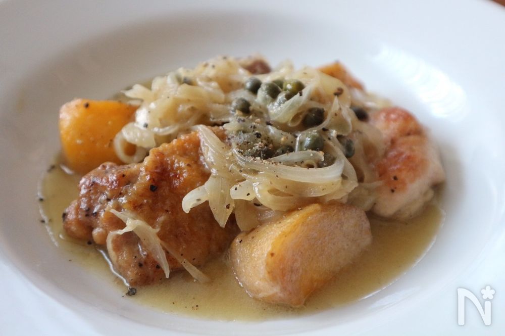 白色の皿に盛られた鶏もも肉と柿の煮込み