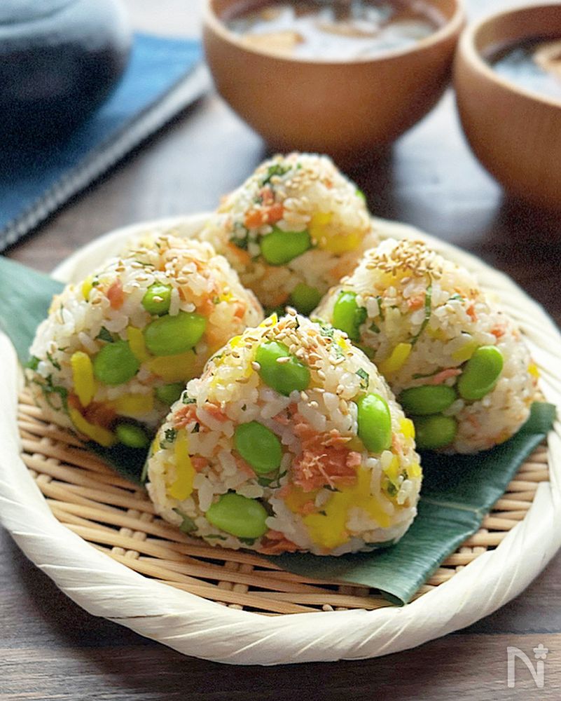 竹ざるに盛られた鮭とたくあんの枝豆入りおにぎり