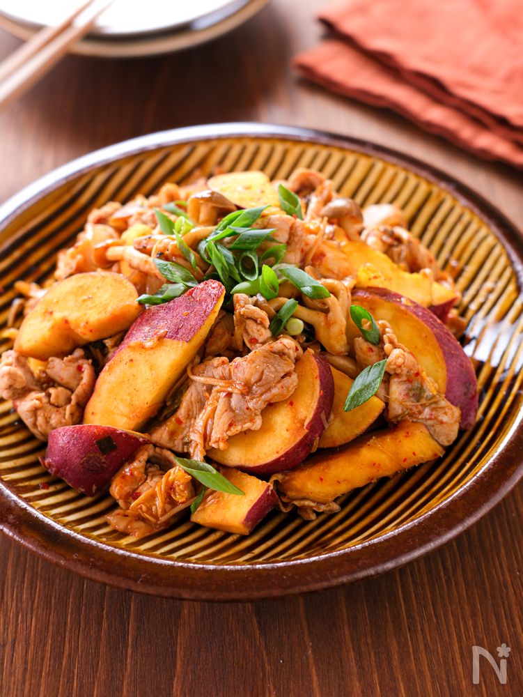 茶色の丸皿に盛られたさつまいもときのこの豚キムチ炒め