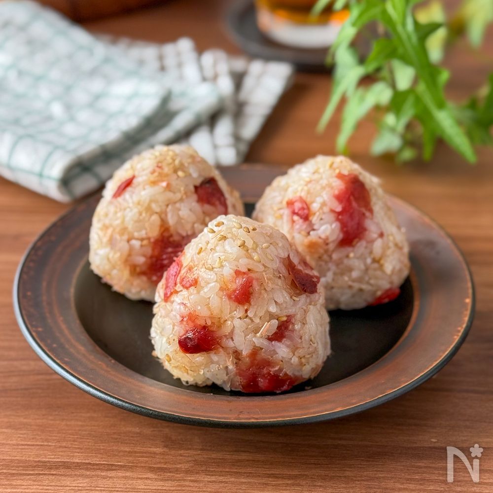 茶色の丸皿にかつおぶしと梅のおにぎりが3個置かれている