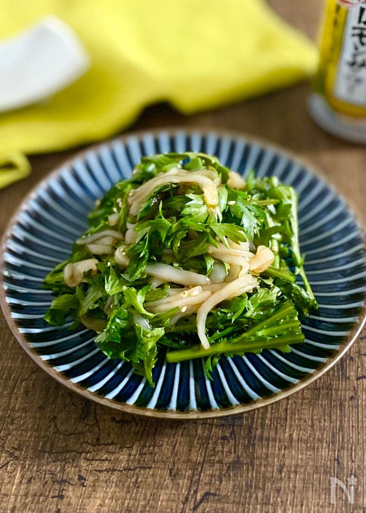 紺色と白色の縞模様の丸皿に盛られた春菊といかのコチュジャンサラダ