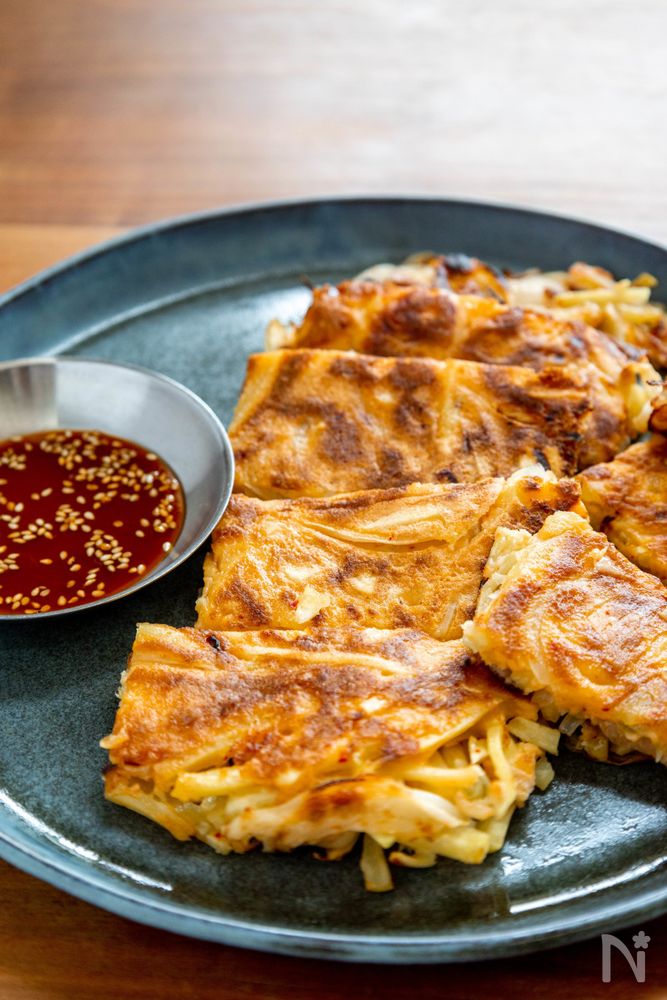 濃い緑色の皿に盛られたさつまいもと玉ねぎのチヂミ