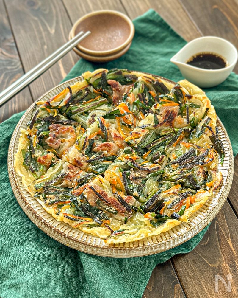 白色の丸皿に盛られた豚肉とニラのチヂミ