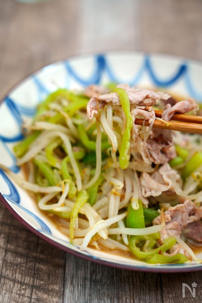 皿に盛り付けた豚肉とヘチマの炒め物を箸で取る様子
