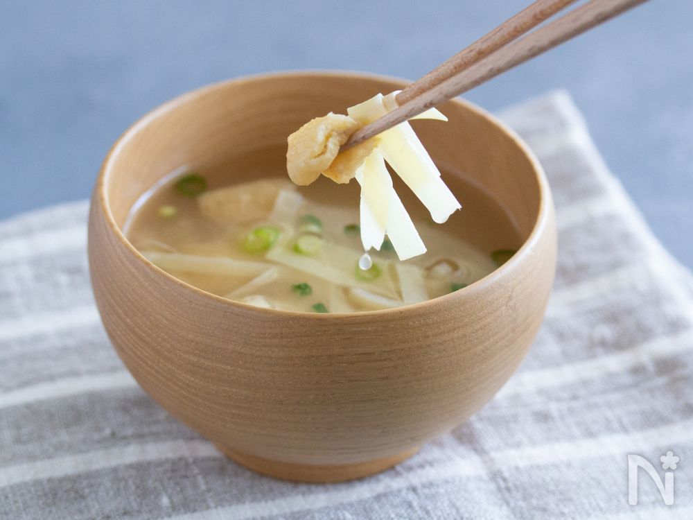 姫皮と油揚げの味噌汁を箸で持ち上げているところ